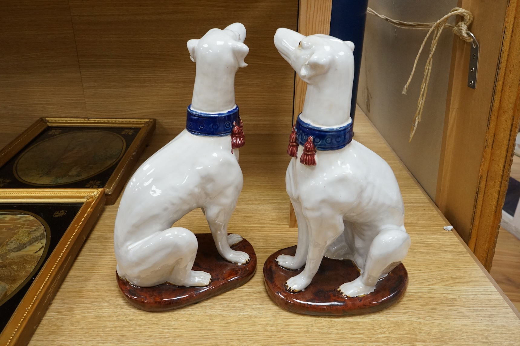 A pair tin glaze models of seated dogs, possibly Greyhounds. 36cm high.
